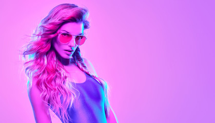 High Fashion neon light. Glamour Sexy Girl with Trendy Wavy Hairstyle, Stylish Sunglasses. Creative Bright Portrait, Pink purple Color. Design Art concept, party Disco vibrations