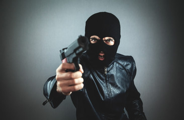 Aggressive man in a black mask with a pistol.