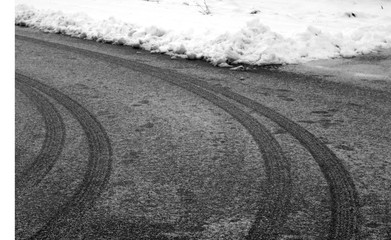 Car tyre prints on frosty road in black and white.