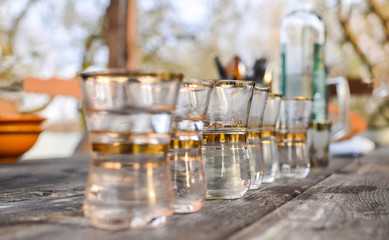 Glass cups with gold border for alcohol closeup on a wooden table. Bar, restaurant, party, outdoor party