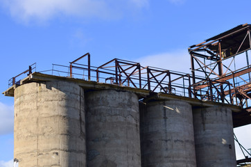 Large reinforced concrete pipe construction with a metal ladder against a bright blue sky. Abandoned Cement Plant