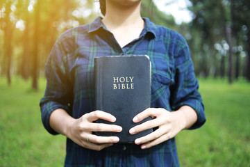 A woman is holding and hug the bible in the morning. Hands folded in prayer on a Holy Bible in life concept. worship and religion. copy space