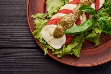 Delicious caprese salad with ripe tomatoes and mozzarella cheese with fresh basil leaves. Italian food.