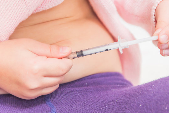 Girl Child Is Doing The Insulin Shot In The Stomach On A Background Of White Brick Wall