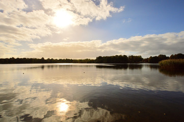 Pochmurny dzień nad jeziorem i słońce za chmurami.