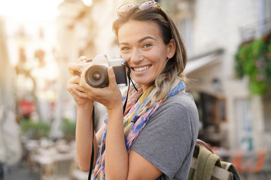 Attractive young woman taking photographs on SLR