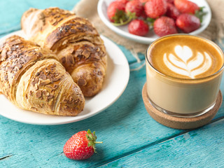 Closeup cappuccino coffee, croissants and fresh strawberries.