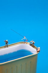 Miniature people fishing on cans