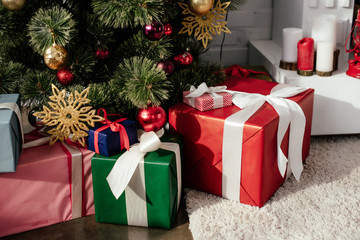 gift boxes under christmas tree with baubles in room