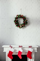 fireplace with christmas stockings and fir wreath with baubles hanging on brick wall in room