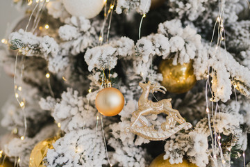 Christmas tree with colorful balls, toys and garlands, bokeh and Christmas lights. Blurred winter ornaments. New Year decorations. Coziness, celebration, winter, feast, holidays concept.