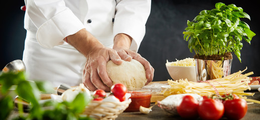 Chef kneading raw dough for an Italian pizza