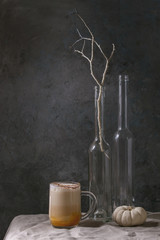 Glass of pumpkin layered spice latte with pumpkin puree, milk foam and cinnamon standing with...