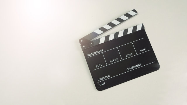 Clapper board or movie slate use in video production or movie and cinema industry in flare light. It's black color on white background.