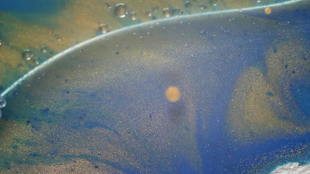 Golden and shiny blue liquid flowing paint. Magic slow motion. Hypnotic macro movement of fluids