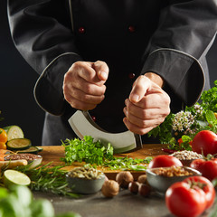 Chef using a mezzaluna knife to chop herbs
