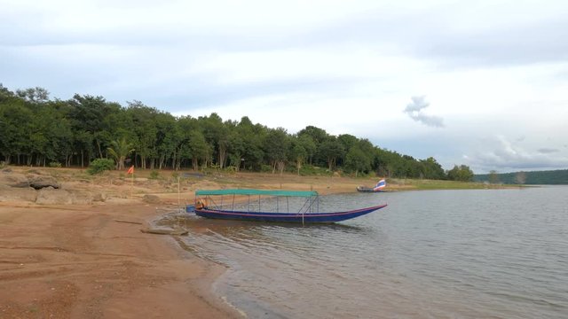 The old boat on the beach of reservoir dam big river against forest with sunset afternoon ambient