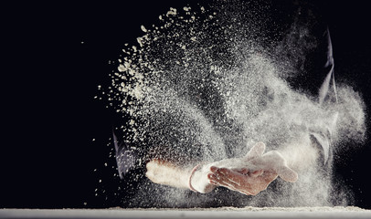 Flour spraying into air while man wipes his hands - obrazy, fototapety, plakaty