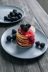 Pancakes with blackberries on a gray plate on a wooden table