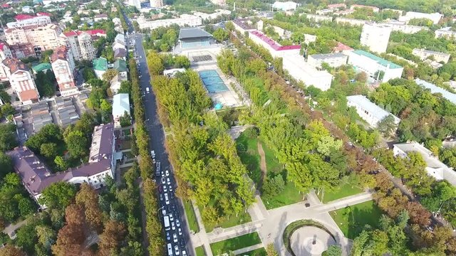 Aerial drone footage overhead traffic car on road, fountain, through avenue of trees. Aerial photo of downtown monuments, autumn trees, flowerbeds street Avenue in Krasnodar 4K.