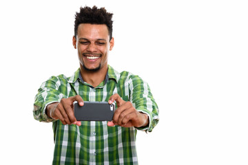 Studio shot of young happy African man smiling while taking pict