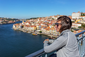 The girl on the bridge of San Luis in the Portuguese city of Porto. Looks at the landscape.