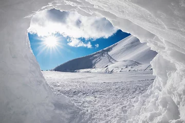 Fotobehang Uitzicht vanaf de sneeuwgrot op besneeuwd winterlandschap met zon © SusaZoom