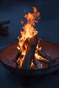 Feuerpfanne mit brennenden Holzscheiten Hochformat