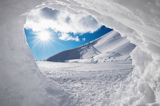 Blick aus der Schneeh&ouml;hle auf verschneite Winterlandschaft mit Sonne