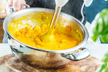 Chef with blender make Pumpkin soup in Kitchen