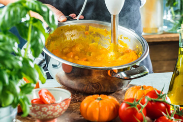 Chef with blender make Pumpkin soup in Kitchen