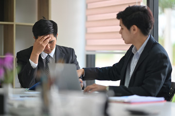 Two Asian colleagues stressed on business paperwork in office