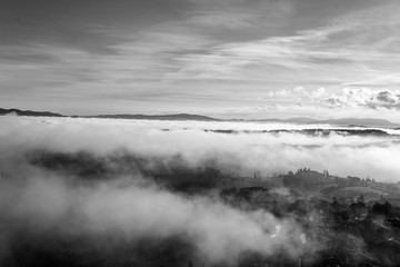A beautiful view of the hills in Tuscany submerged by a morning mist that gives a magical touch to the scene from the top of one of the towers of San Gimignano