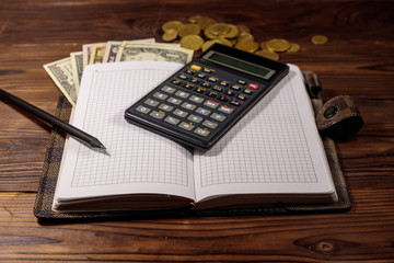 Notepad with dollars, pencil and calculator on wooden desk. Financial planning concept