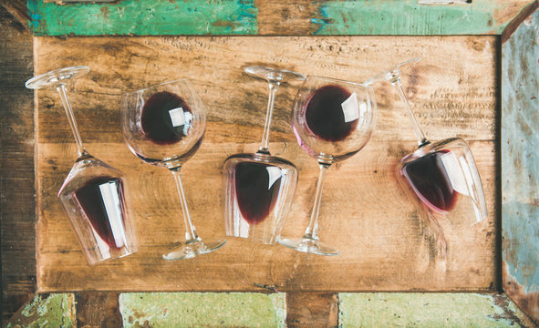 Flat-lay of red wine in glasses over rustic wooden tray background, top view. Wine bar, winery, wine tasting concept