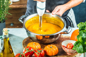 Chef with blender make Pumpkin soup in Kitchen