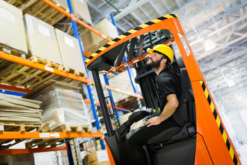 Warehouse worker doing logistics work with forklift loader © NDABCREATIVITY