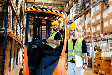 Warehouse workers working together with forklift loader © NDABCREATIVITY
