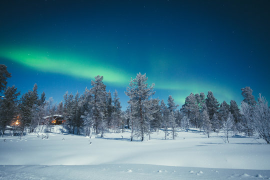 Aurora Borealis over winter wonderland scenery in Scandinavia