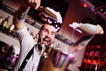 the bartender at a party in a nightclub pours ice for cocktails and screams happily against the bar