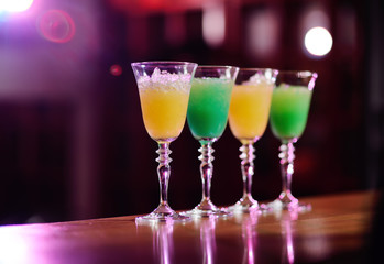 four cocktails of yellow and green flowers on the bar close-up