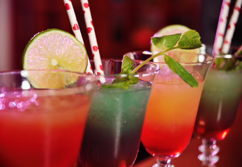 beautiful fresh alcoholic cocktails with mixed colored layers on the background of a bar in a nightclub.