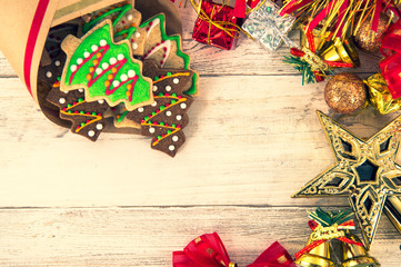 Beautiful Christmas composition and decoration with baked Christmas gingerbread cookie in paper bag on light wooden background, flat lay, top view, copy space (text space)