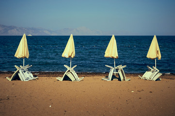 A number of white beach umbrellas and sun beds. Coast of the Aegean Sea of Turkey.