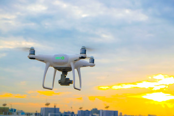 Drone flying on sunset sky in city building