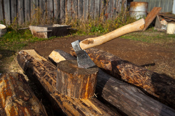 Iron ax with a wooden handle in a tree deck. Stump giving summer in the background of a green grass glade sunny day