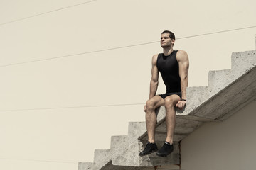 Athletic man sitting on ascending concrete stairs