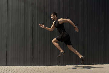 A side view shot of a fit young, athletic man jumping and runnin