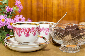 cups and chocolate in a crystal vase on a wooden table near a po
