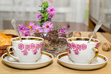 two tea cups and chocolate on a wooden table